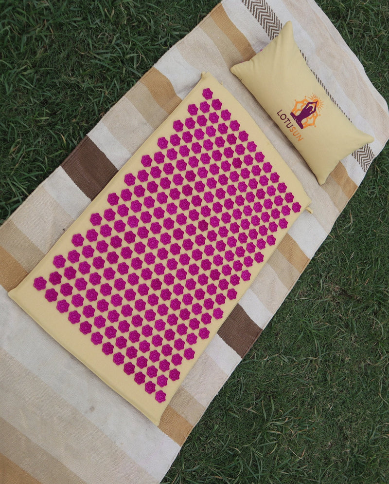 Top-down view of the LotuSun mat and pillow on a wide oak floor with a wooden yardstick beside for scale.